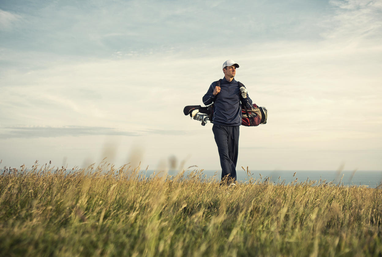 A male adult golfer walks to the green atop a links golf course in Woolacombe North DevonEngland.