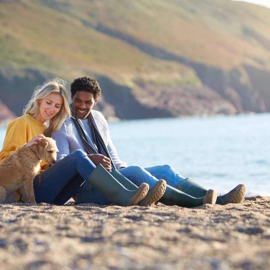 Couple with dog on beach whilst on Autumn holiday in North Devon