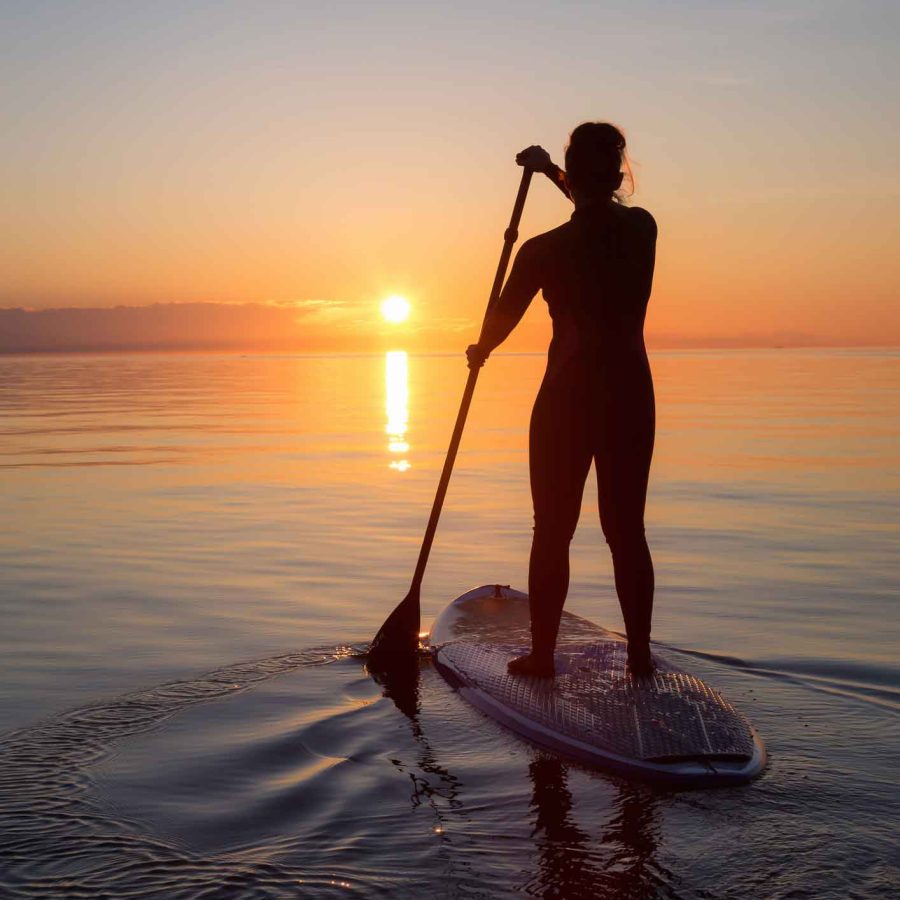 woman paddle boarding at sunset in Devon
