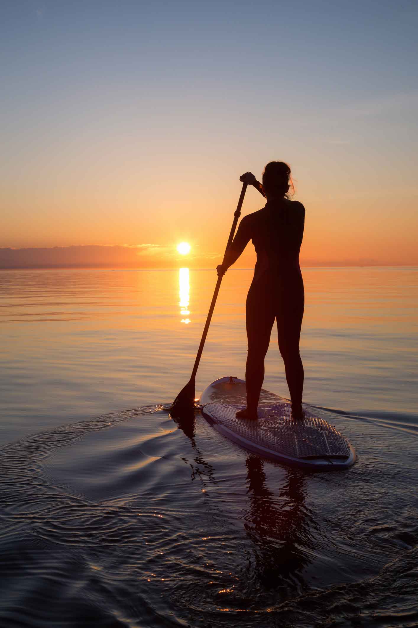 woman paddle boarding at sunset in Devon