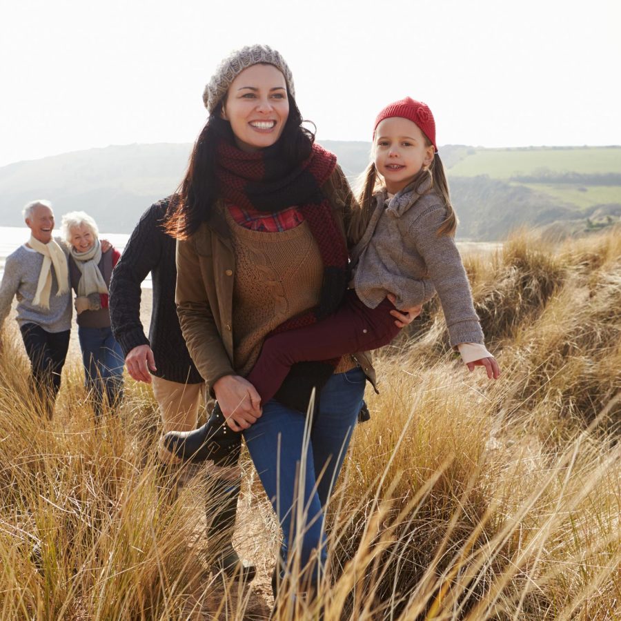 Multi Generation Family In Sand Dunes On Winter Beach Walking