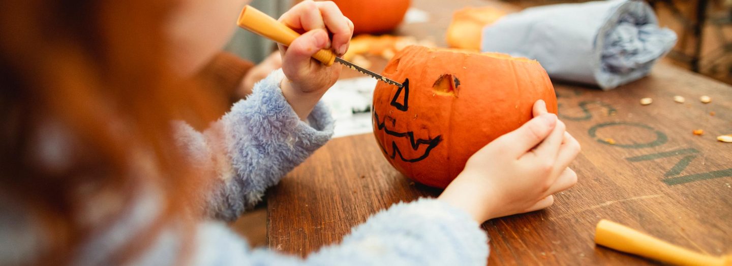 Family with children carving pumpkins at a farm after picking them at a farm in preparation for Halloween.