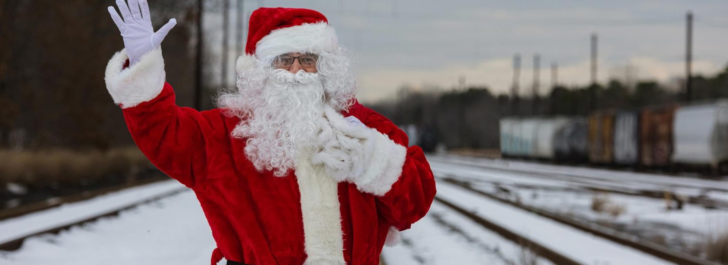 Man dressed as Father Christmas stood by train