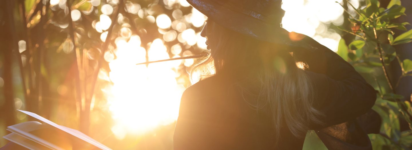 A woman dressed as a witch standing in a woods reading a story