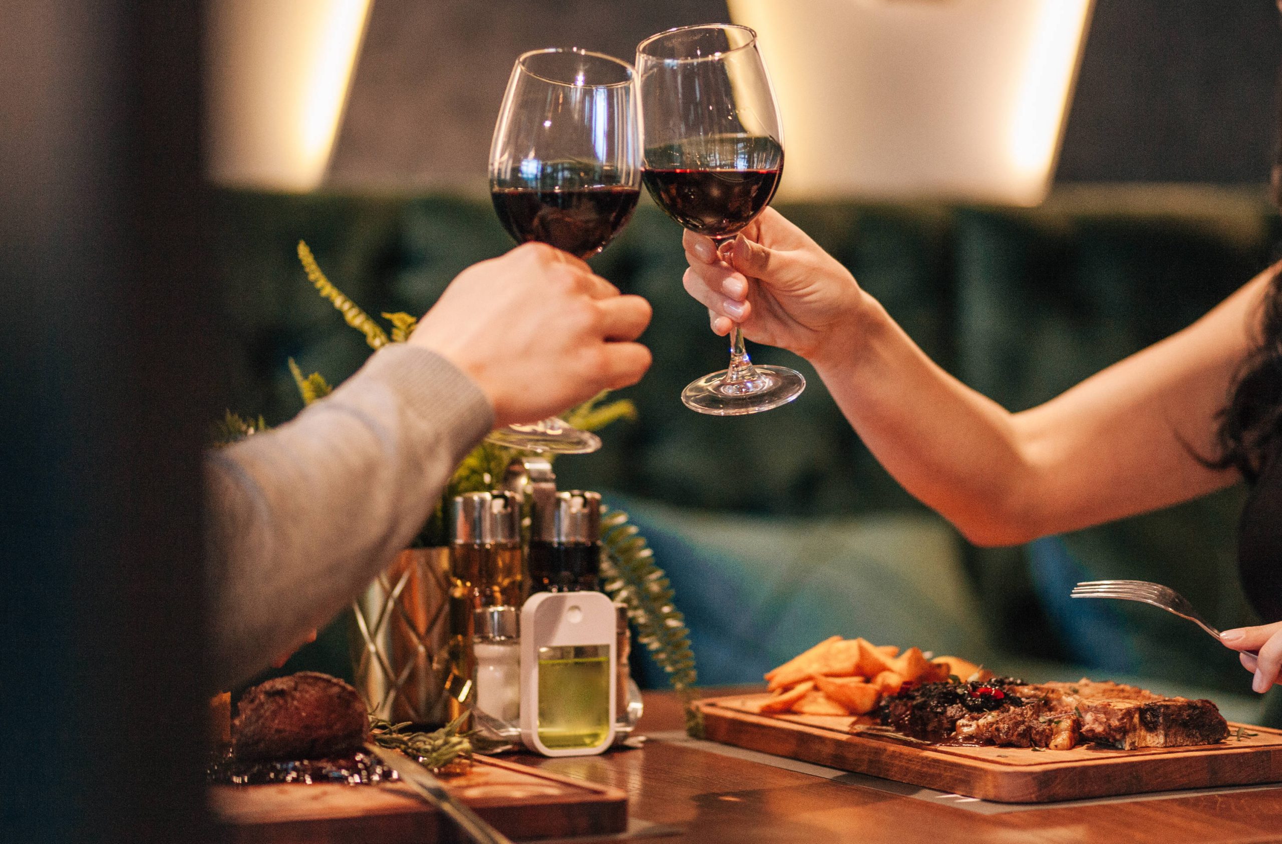 Couple toasting red wine glasses over a romantic meal